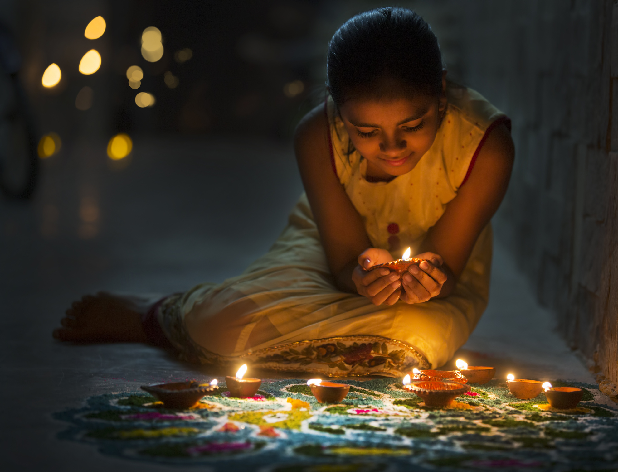 Jeune fille faisant du rangoli et décorant avec des lampes à huile pour Diwali